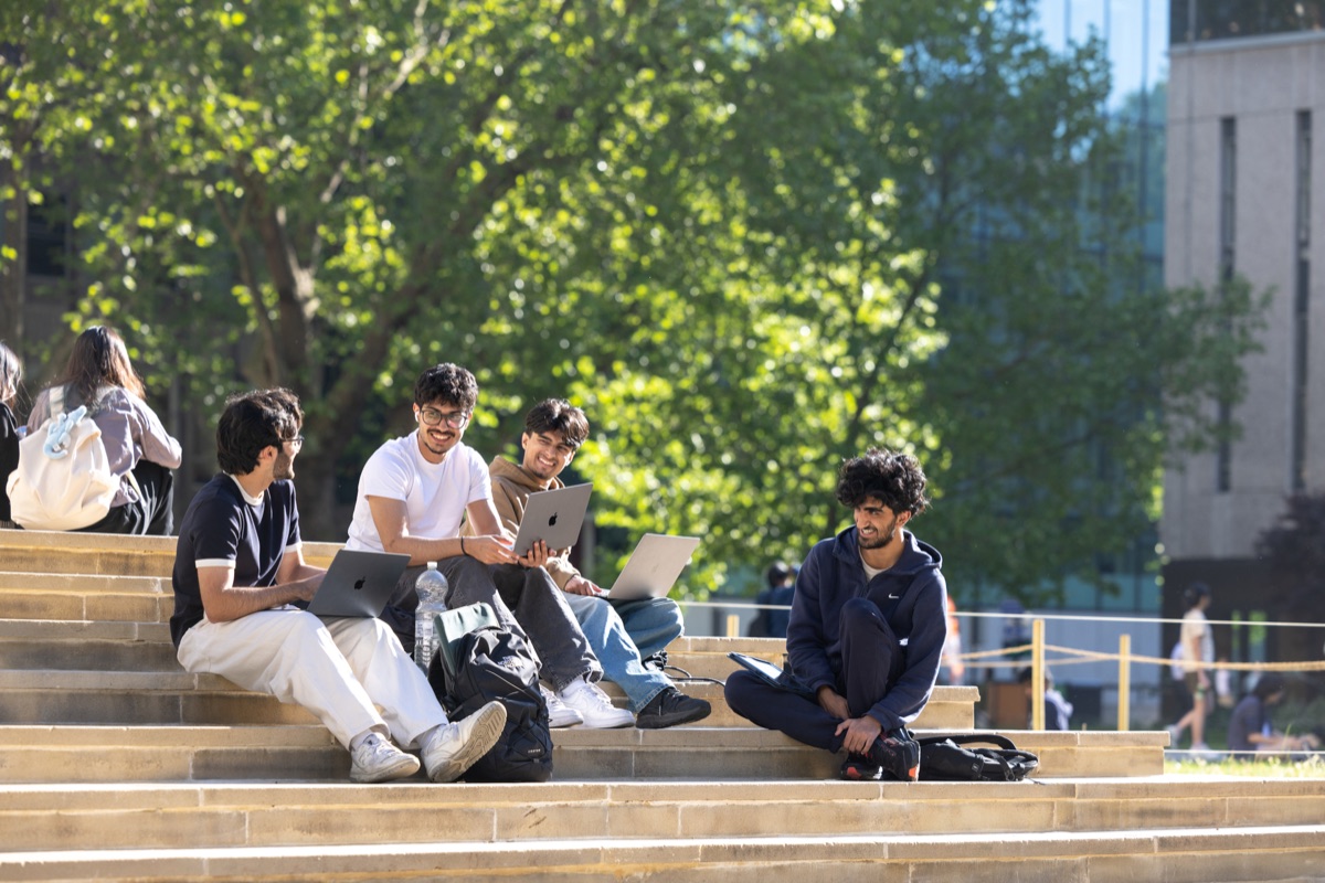 Students working on laptops on the steps of Queen's Lawn at Imperial's South Kensington campus